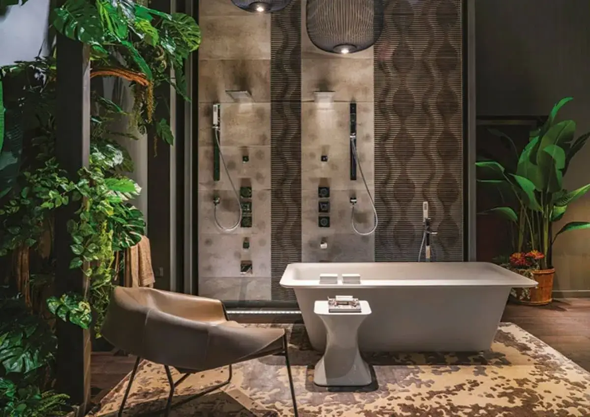 Une salle de bain luxueuse avec une douche à jets multiples, une baignoire îlot, un fauteuil design et une végétation luxuriante. Une belle idée salle de bain douche pour une ambiance tropicale.