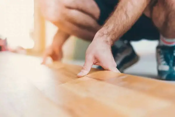 Pose d'une sous couche parquet sur carrelage. Un homme pose délicatement une fine couche isolante avant la pose du parquet.