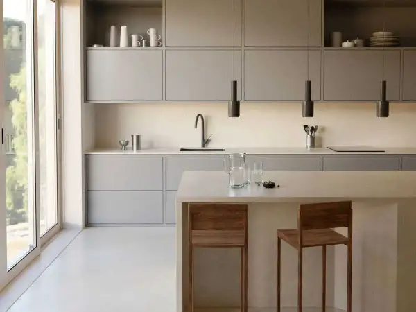 Élégante cuisine couleur taupe, avec des meubles bas et hauts épurés, un îlot central et des tabourets en bois.