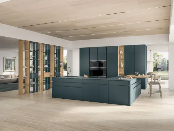 Un sol de cuisine tendance en travertin clair, réchauffant cet espace moderne aux meubles bleu pétrole.