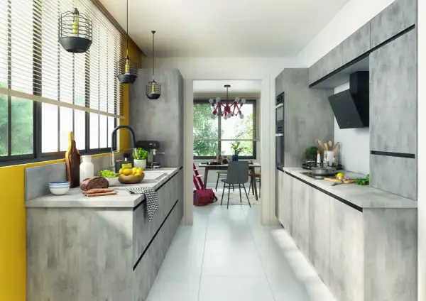 Cuisine moderne avec des meubles gris béton, une cuisine en parallèle fonctionnelle et un espace repas lumineux visible à travers une arche.