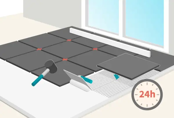Pose de carrelage au ciment : une nouvelle dalle est posée sur la colle fraîche. Un marteau et une spatule sont prêts. Le séchage prend 24h.