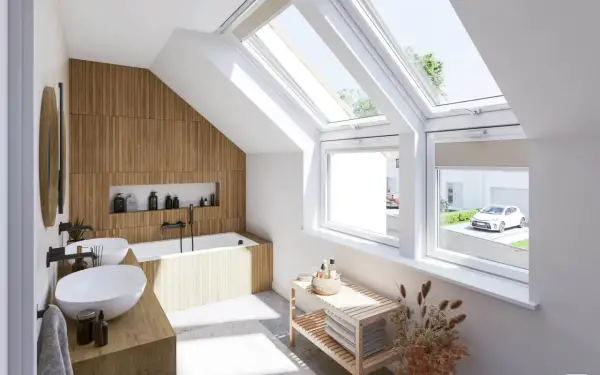Salle de bain sous pente lumineuse avec murs en bois, baignoire, double vasque et grandes fenêtres de toit offrant une vue sur un jardin.
