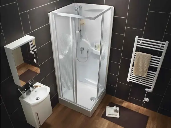 Salle de bain moderne avec une cabine de douche aux dimensions compactes, un lavabo suspendu et un sèche-serviettes.