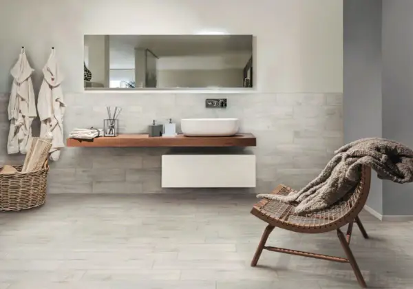 Salle de bain moderne avec murs et sol en grès cérame émaillé effet bois, lavabo suspendu, fauteuil confortable.