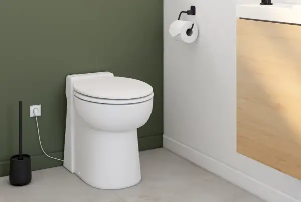Toilettes modernes avec brosse et prise électrique. Le wc broyeur, discret, est prêt à fonctionner.