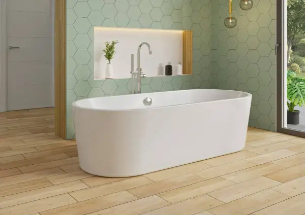 Une élégante baignoire îlot blanche trône sur un parquet en bois clair, sous un mur aux carreaux hexagonaux vert menthe.